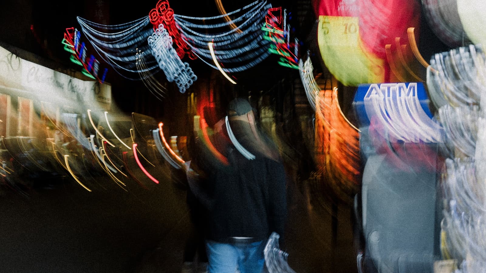 Person in a black jacket standing on a city street at night.